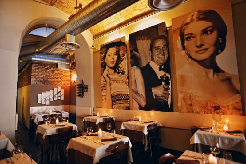 Ristorante Fellini sala in penombra con tavoli  apparecchiati e Alberto Sordi