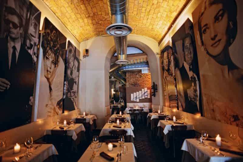 Ristorante Fellini sala in penombra con tavoli apparecchiati