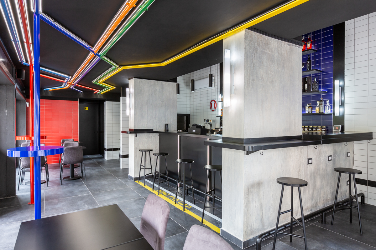Knock Street Bar sala con bancone, sedie, tavoli, sgabelli e illuminazione neon