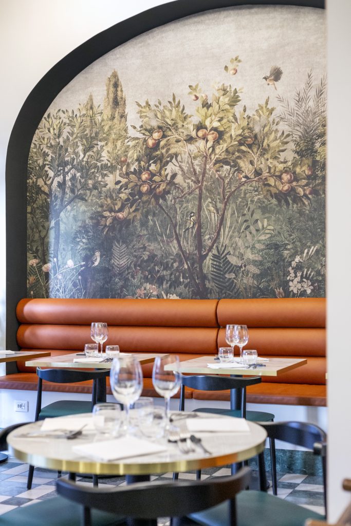 Ristorante Emasi tavolini con sedie e parete decorata floreale
