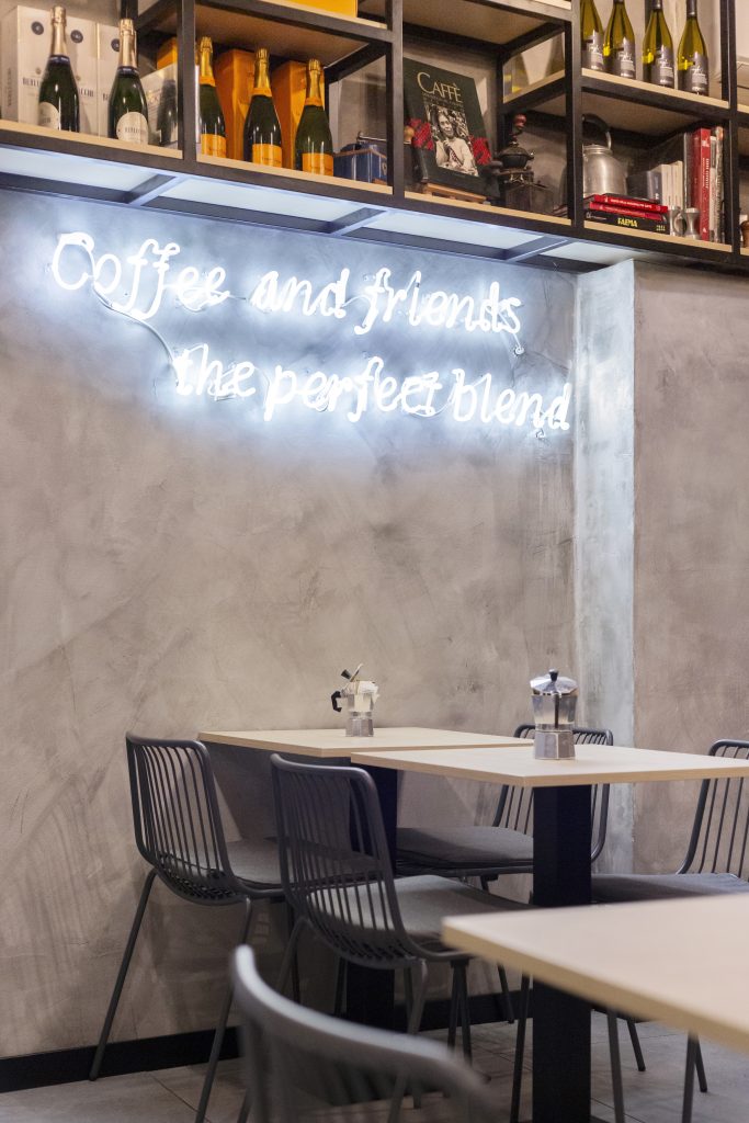 Bar bistrot Tre Caffè, parete con vini e insegna al neon