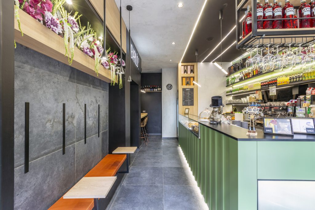 Entrance to an industrial-style cocktail bar with green bar and orange benches