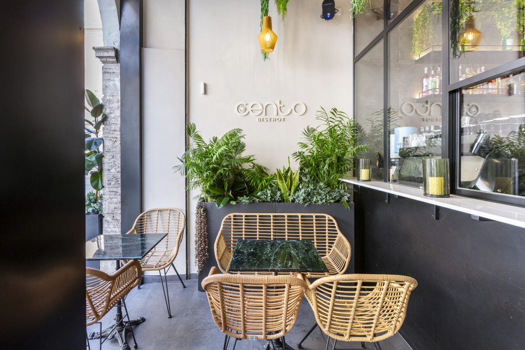 Cento Bistrot dehor con sillas de mimbre y plantas